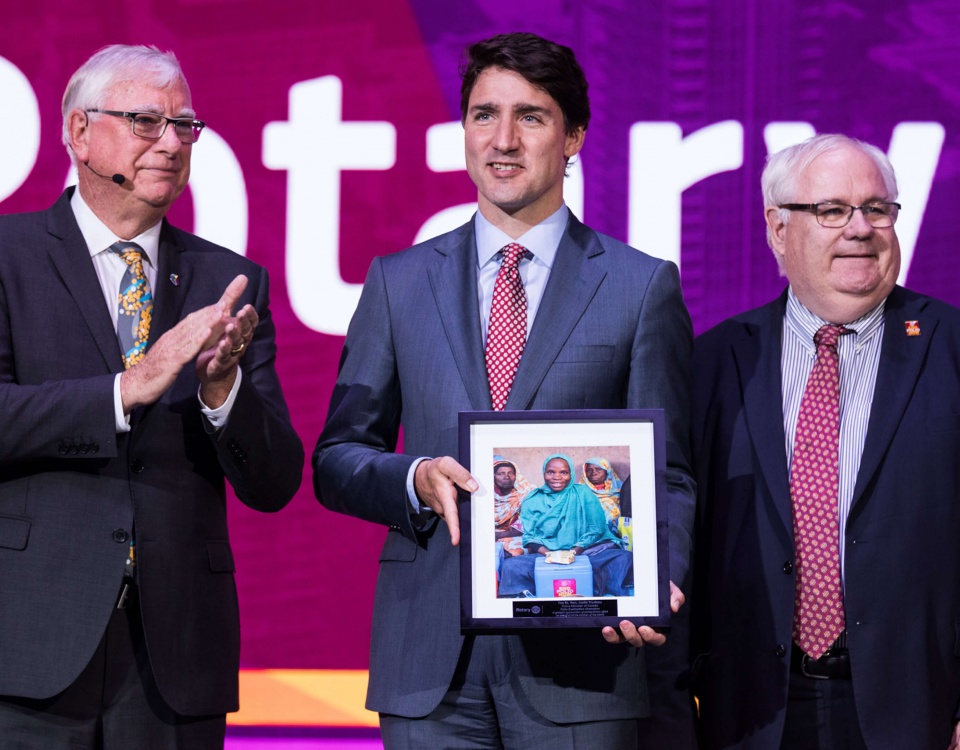 Justin Trudeau on stage with two men at a Rotary International event