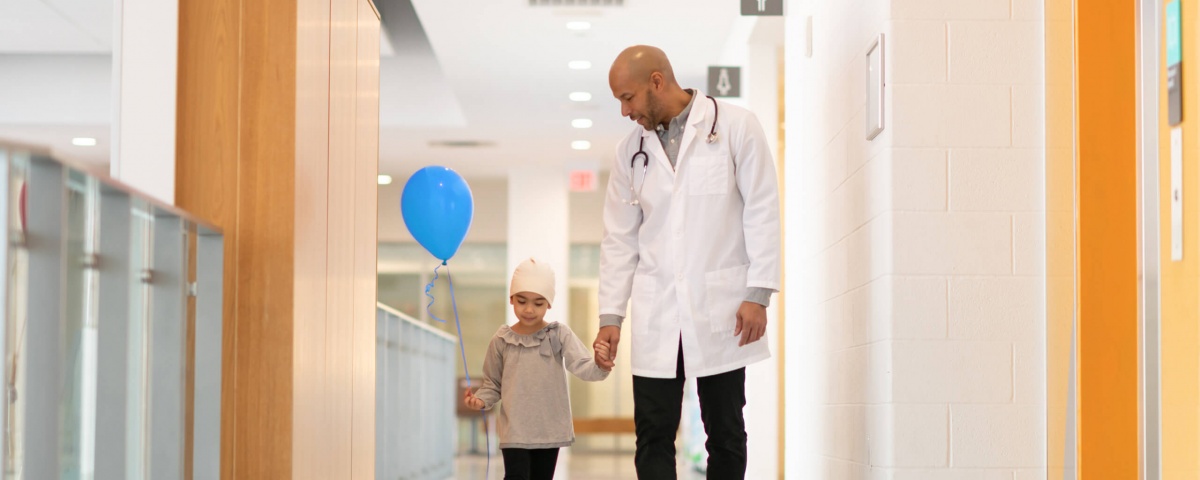SickKids doctor and child walk down hospital halls hand in hand